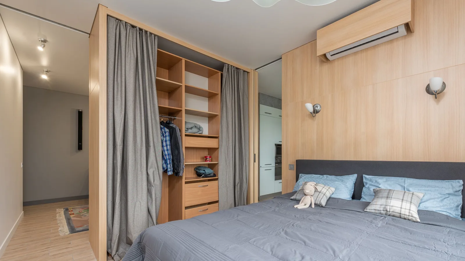 12000 BTU DIY mini split indoor unit boxed in a light wood cover on a bedroom wall above a double bed