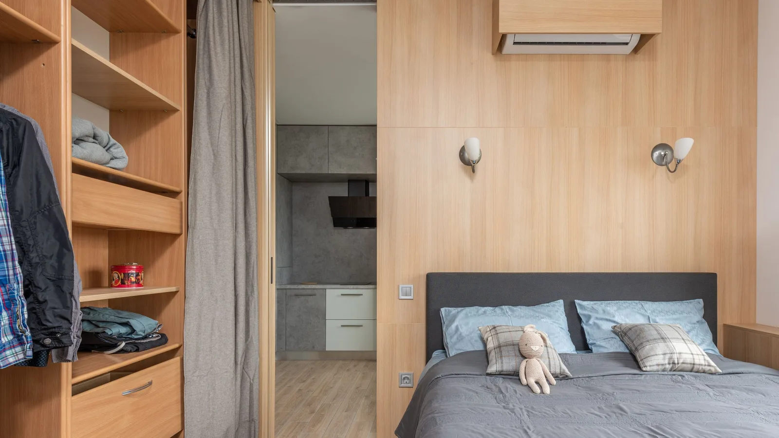 9,000 BTU wall head of a dual zone pre-charged mini split boxed in light wood above a double bed in a small bedroom